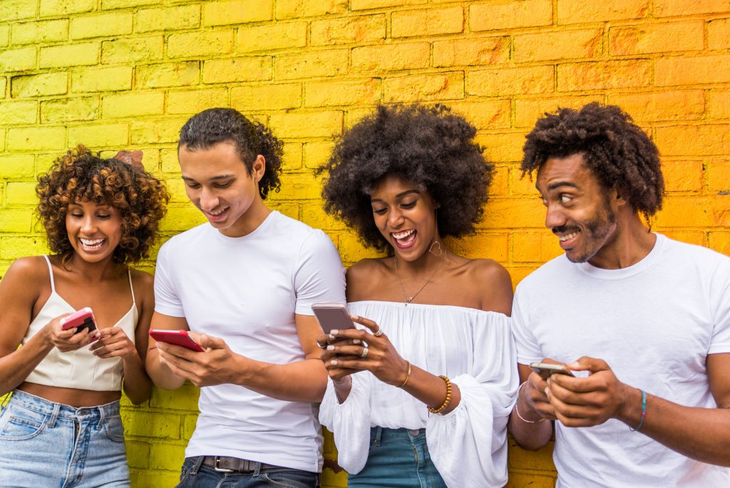 A Group of young african friends enjoying playing games on their mobile phones